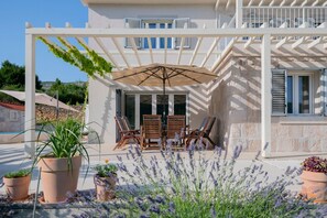 A covered outdoor seating area with a table and chairs, surrounded by potted plants and lavender. - Villa Donari - Early check in & late check out (Tugare)