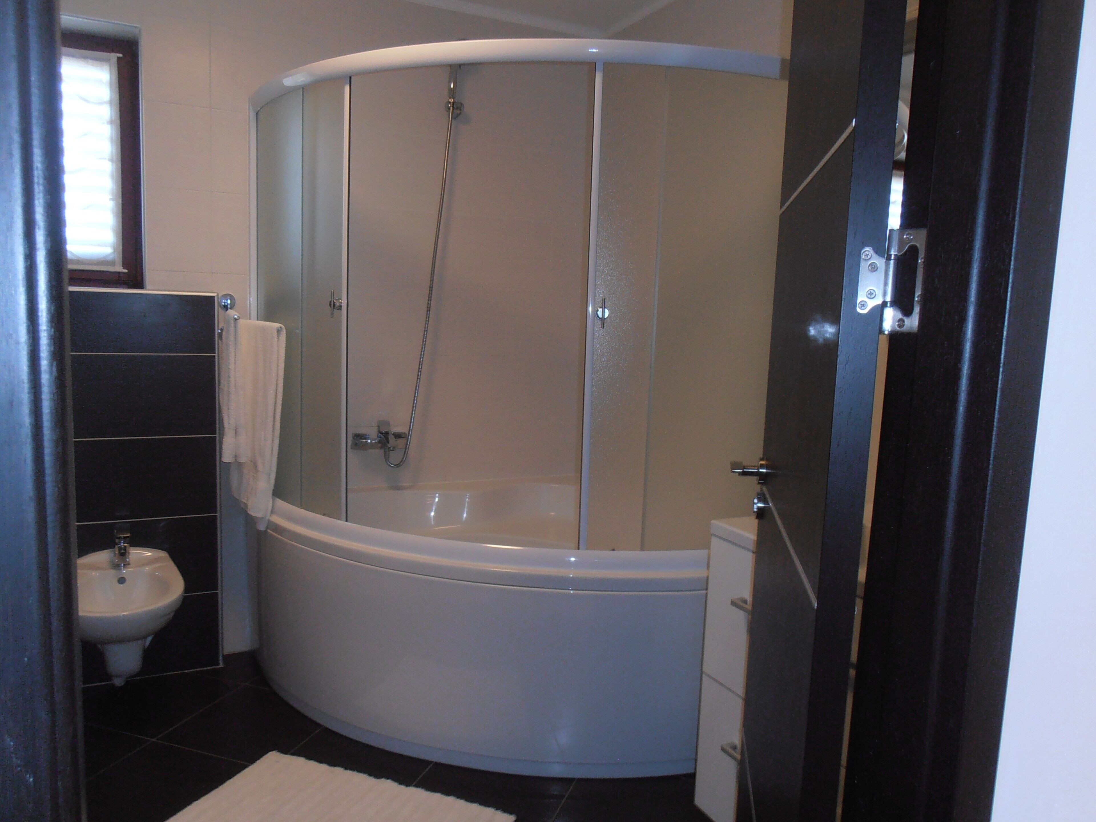 A modern bathroom with a freestanding bathtub, a glass-enclosed shower, and a white sink.