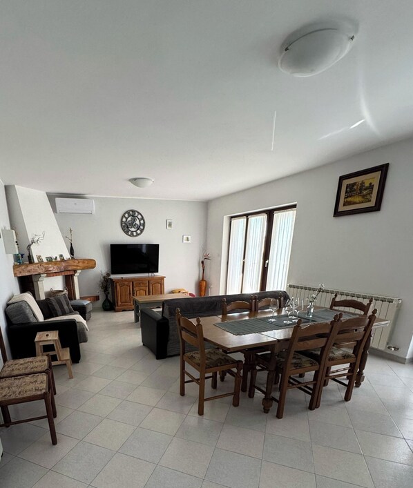 Un salon comprenant une table à manger, des chaises, un canapé, un téléviseur et une cheminée.
