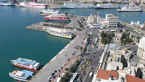 A harbor with multiple cruise ships docked, a busy road with vehicles, and a cityscape in the background. - Elegant and Airy Apartment One Stop from City Center by VillaRentalsgr (Athens)