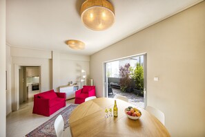 Ein modernes Wohnzimmer mit Essbereich, roten Sofas, einem Holztisch und Blick ins Freie.