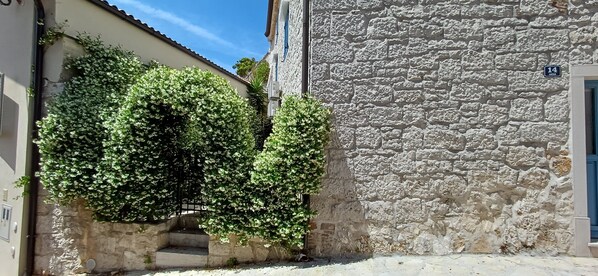 Una calle estrecha con un edificio de piedra y otro con puerta azul.