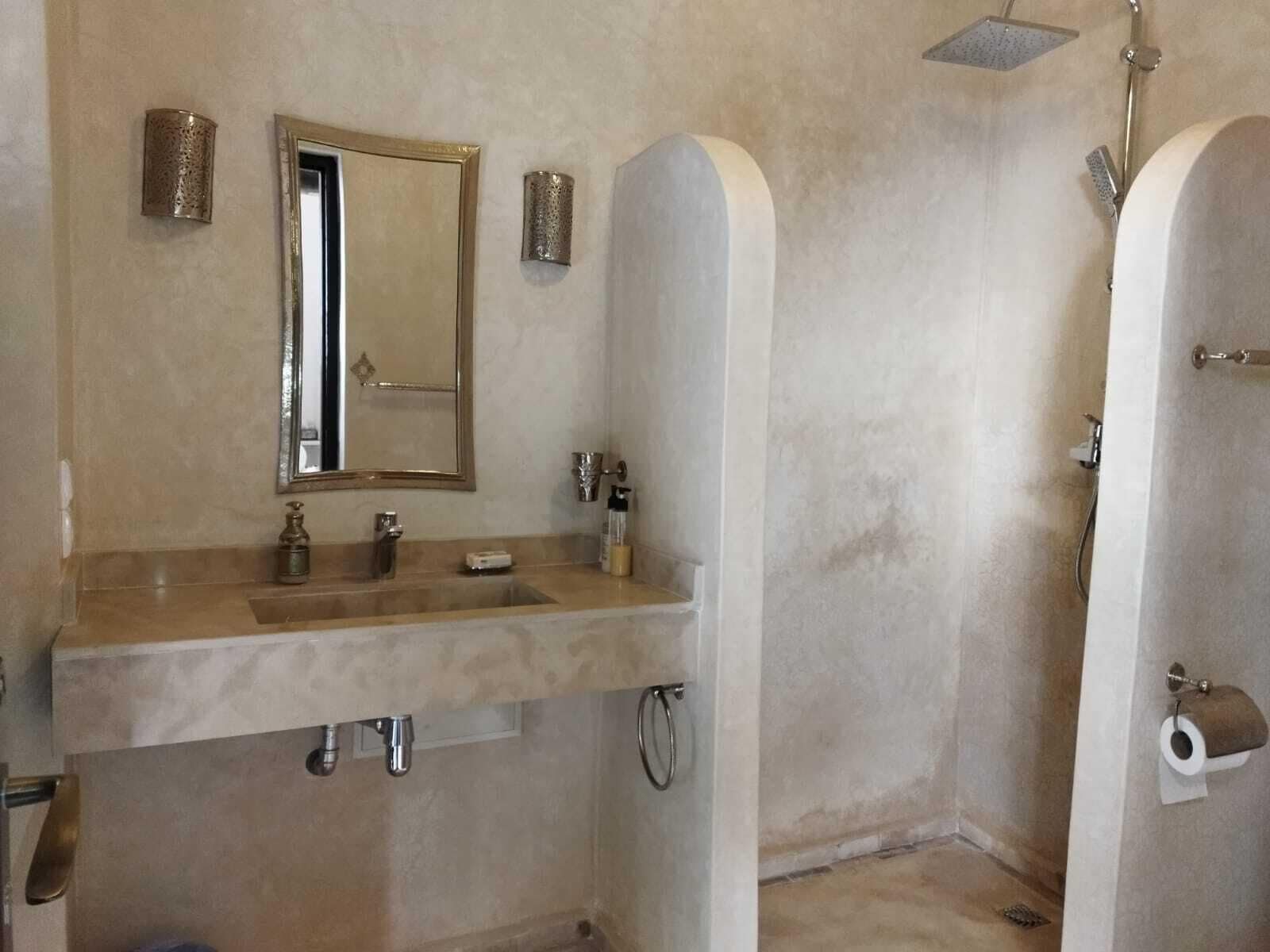A bathroom with a sink, mirror, and shower.