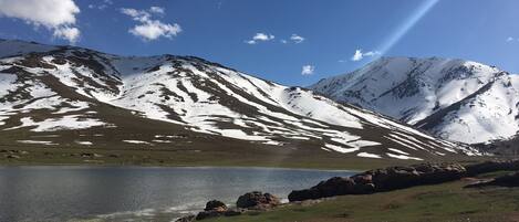 A mountain landscape with a lake and snow-covered peaks.