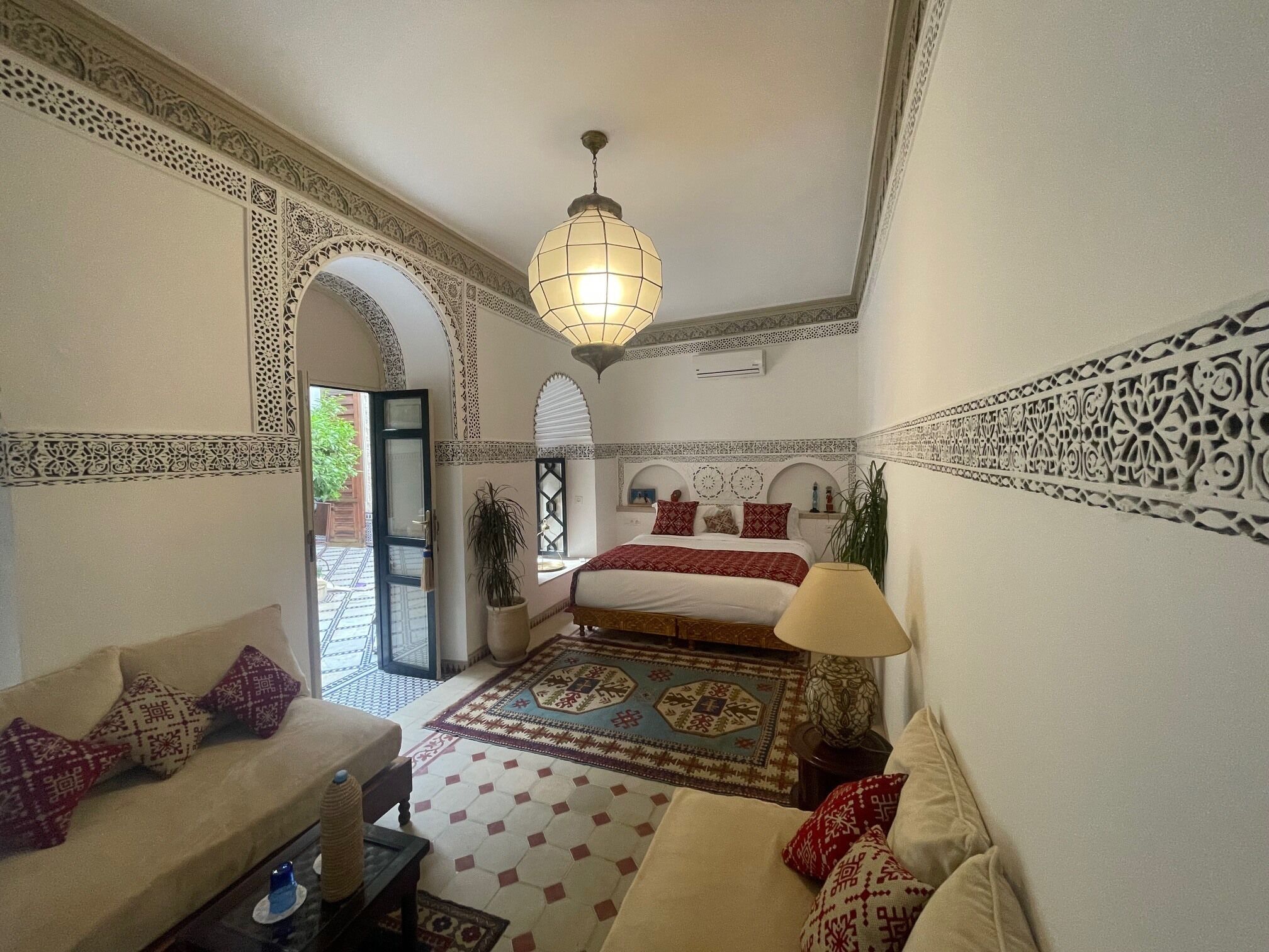 Una habitación con cama, sofá, lámpara y una lámpara colgante.
