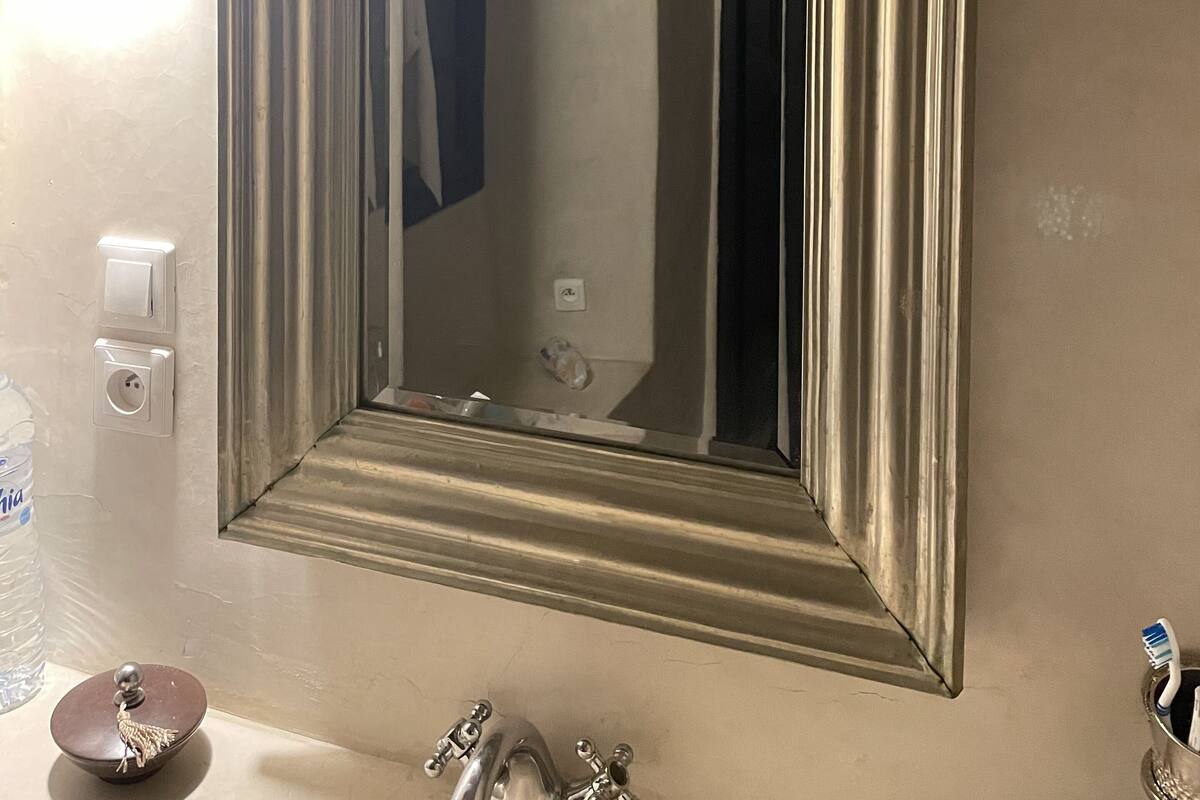 Un baño con un espejo grande, un lavabo, un grifo y un adorno en la pared.