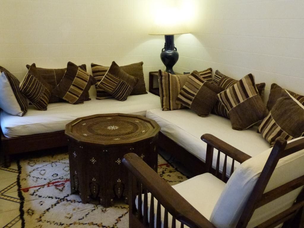 A cozy seating area with a sofa, multiple pillows, a wooden coffee table, and a floor lamp.