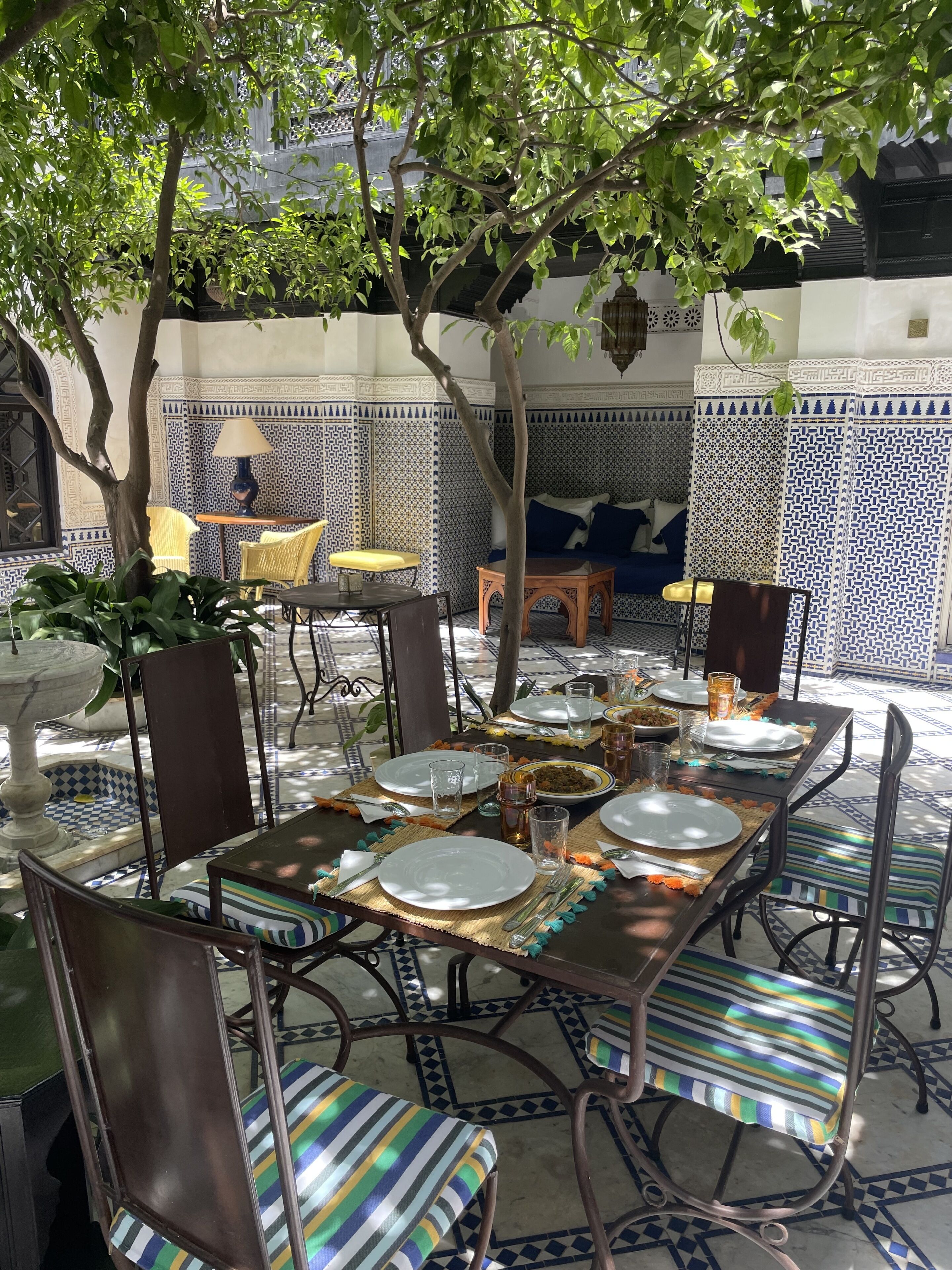 Un coin repas avec une table dressée pour quatre personnes, entourée de chaises dotées de coussins à rayures.