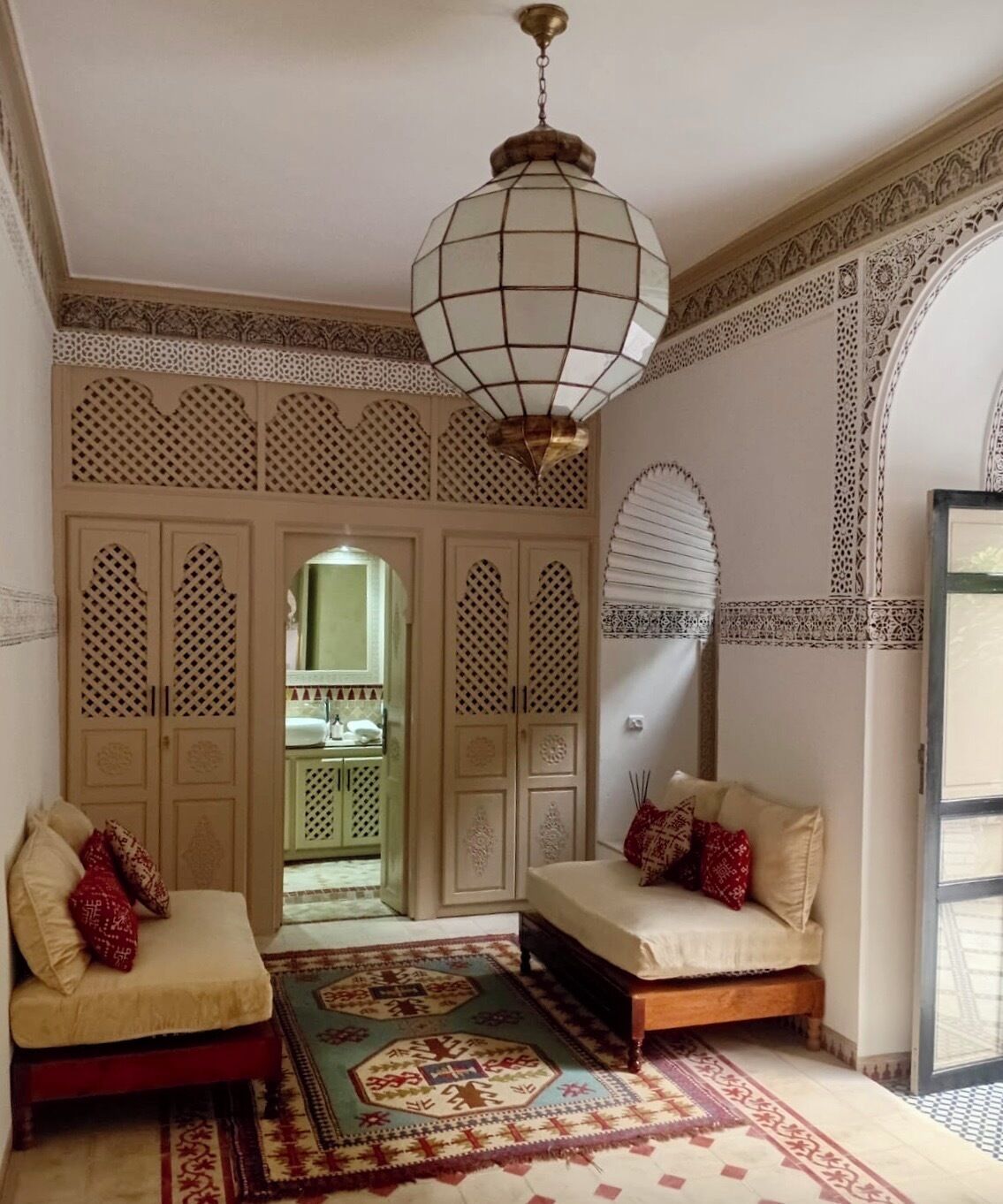 A room with two sofas, a patterned rug, and a hanging light fixture.