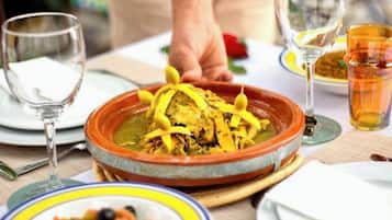Una mesa de comedor con una olla grande de estofado, un tazón de ensalada y varios vasos de agua.