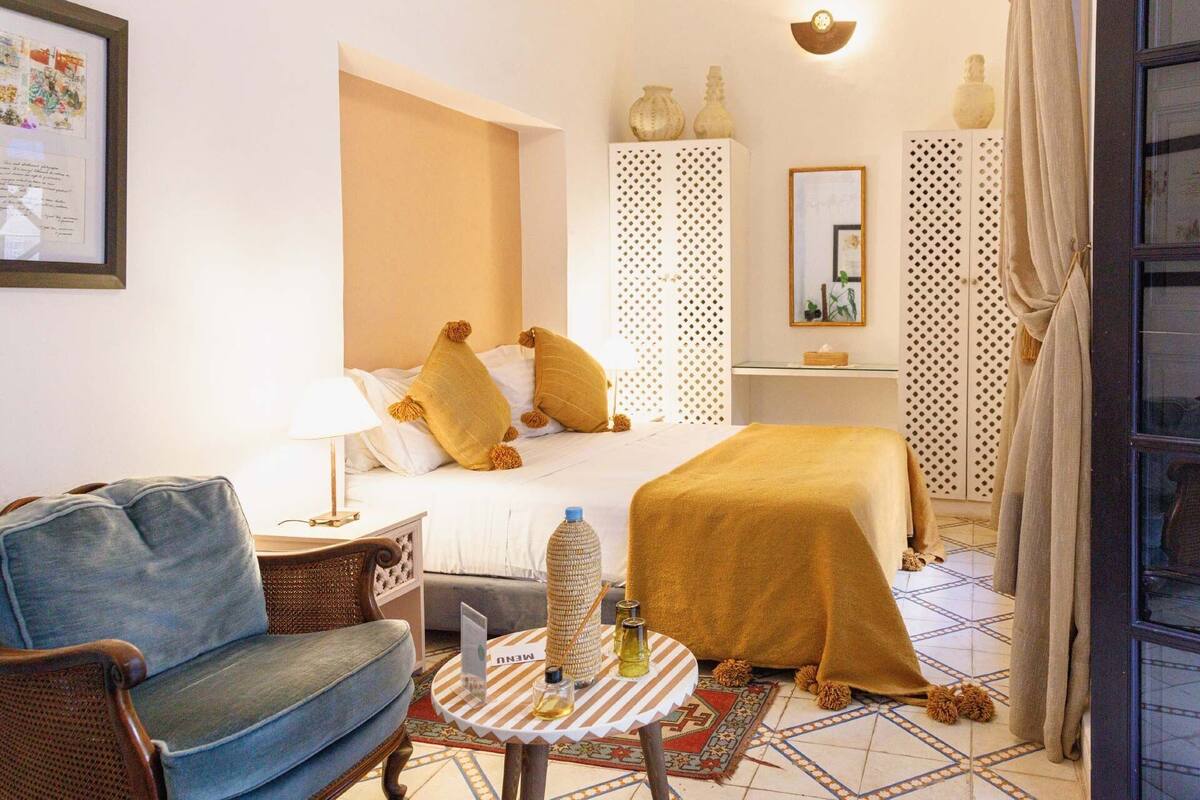 Una habitación de hotel con cama, una silla, una mesita con un menú y elementos decorativos.