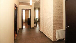 Um corredor com parede de tijolos brancos, um radiador e uma porta.