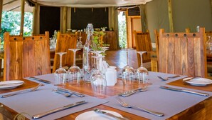 Een eethoek met een houten tafel gedekt voor vier personen, compleet met bestek, borden en wijnglazen.