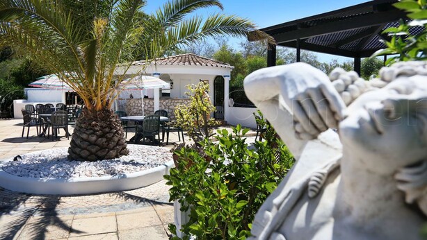 A patio area with outdoor seating, a palm tree, and a stone structure. - Jacuzzi Apartment   (Lagos)