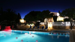 A swimming pool with lounge chairs and a stone wall with decorative patterns. - Jacuzzi Apartment   (Lagos)