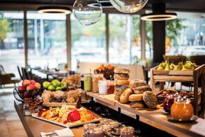 A breakfast buffet with various fruits, pastries, and beverages.