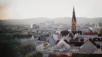 Eine Stadtansicht mit einem markanten Kirchturm, verschiedenen Gebäuden und hügeliger Landschaft im Hintergrund.
