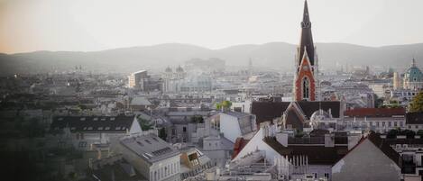 A cityscape with a prominent church tower, various buildings, and a hilly background.