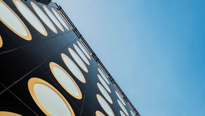 A building facade with a repeating pattern of circular windows and the word "MOOONS" in large letters.