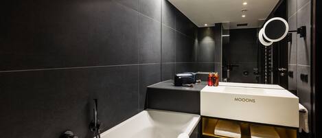 A modern bathroom with a bathtub, a vanity with a mirror, and toiletries.