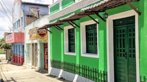 A row of buildings with green facades, a sign for 'Doces JDN', and a motorcycle parked in front. - Pousada Recanto Verde (Sao Benedito do Sul)