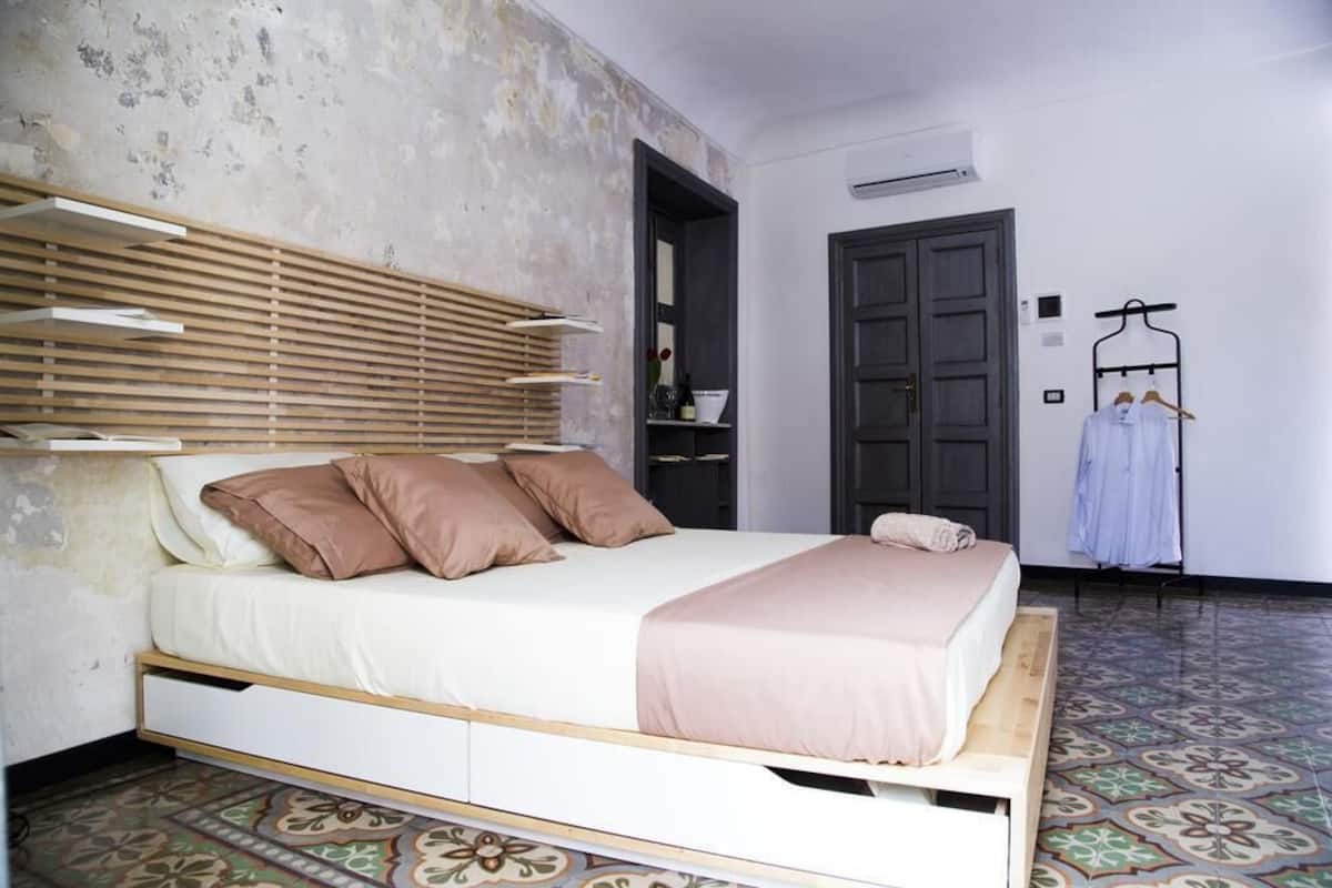 Quarto com cama, ripas de madeira sobre a cama, guarda-roupa e cabideiro.