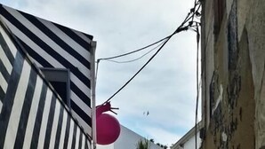 A narrow alleyway with a modern building featuring a black and white striped facade and a red spherical decoration. - Community Rooms & Wine (Favara)
