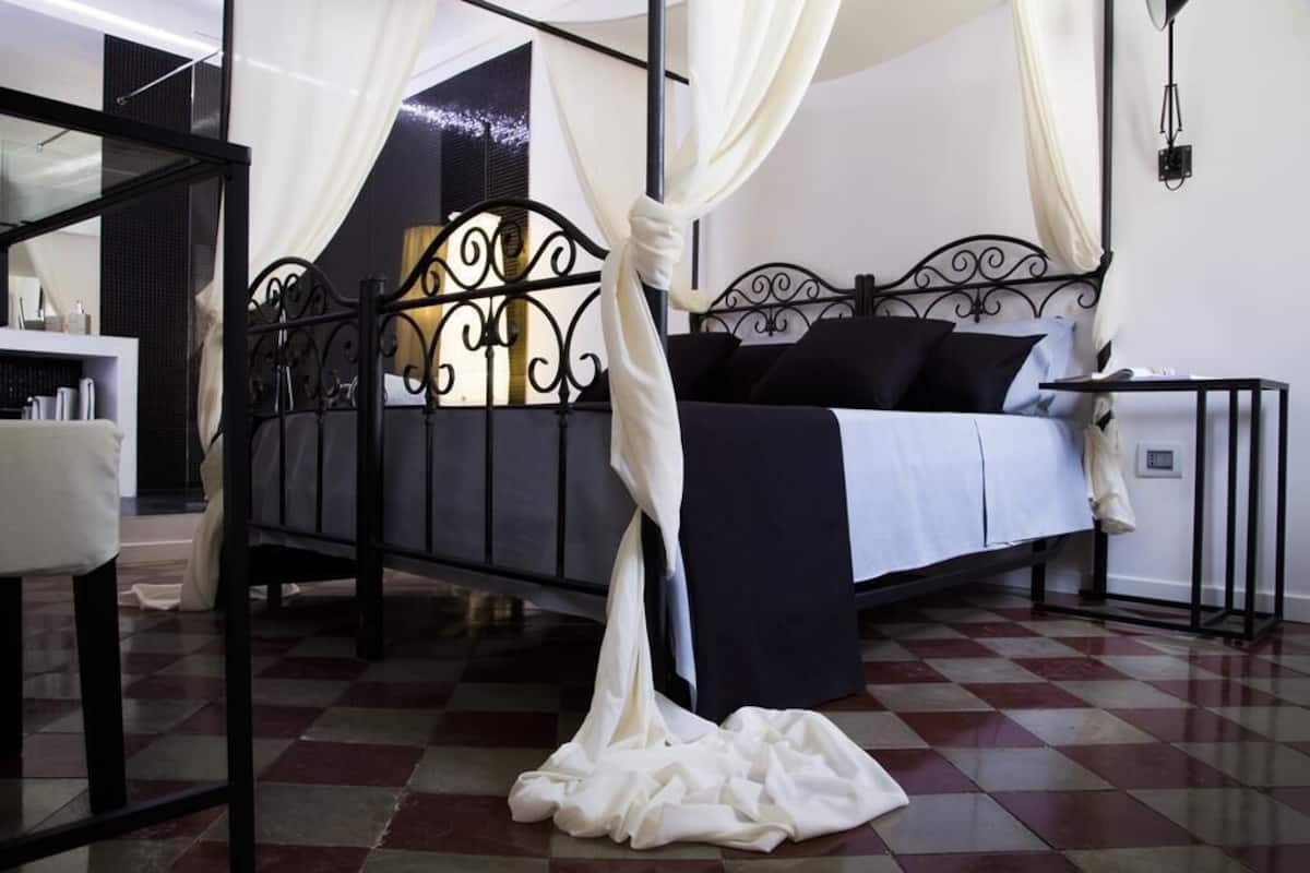 Quarto com cama de dossel, mesa de cabeceira e um espelho grande.