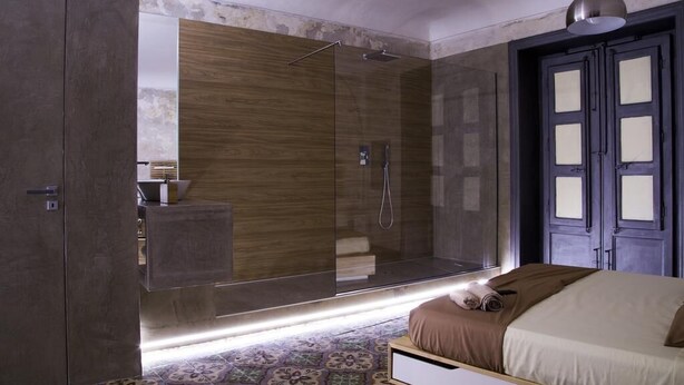A modern bedroom with a large mirror, a walk-in closet, and a shower area. - Community Rooms & Wine (Favara)