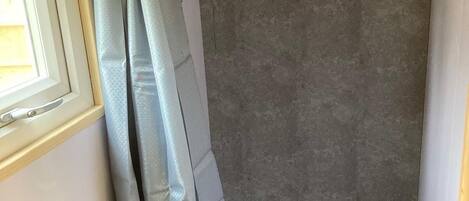 A bathroom with a shower curtain, a sink, and a window.