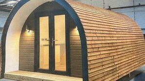 A small, arched wooden structure with a door and a bench outside. - The Pirate Inn (Penzance)