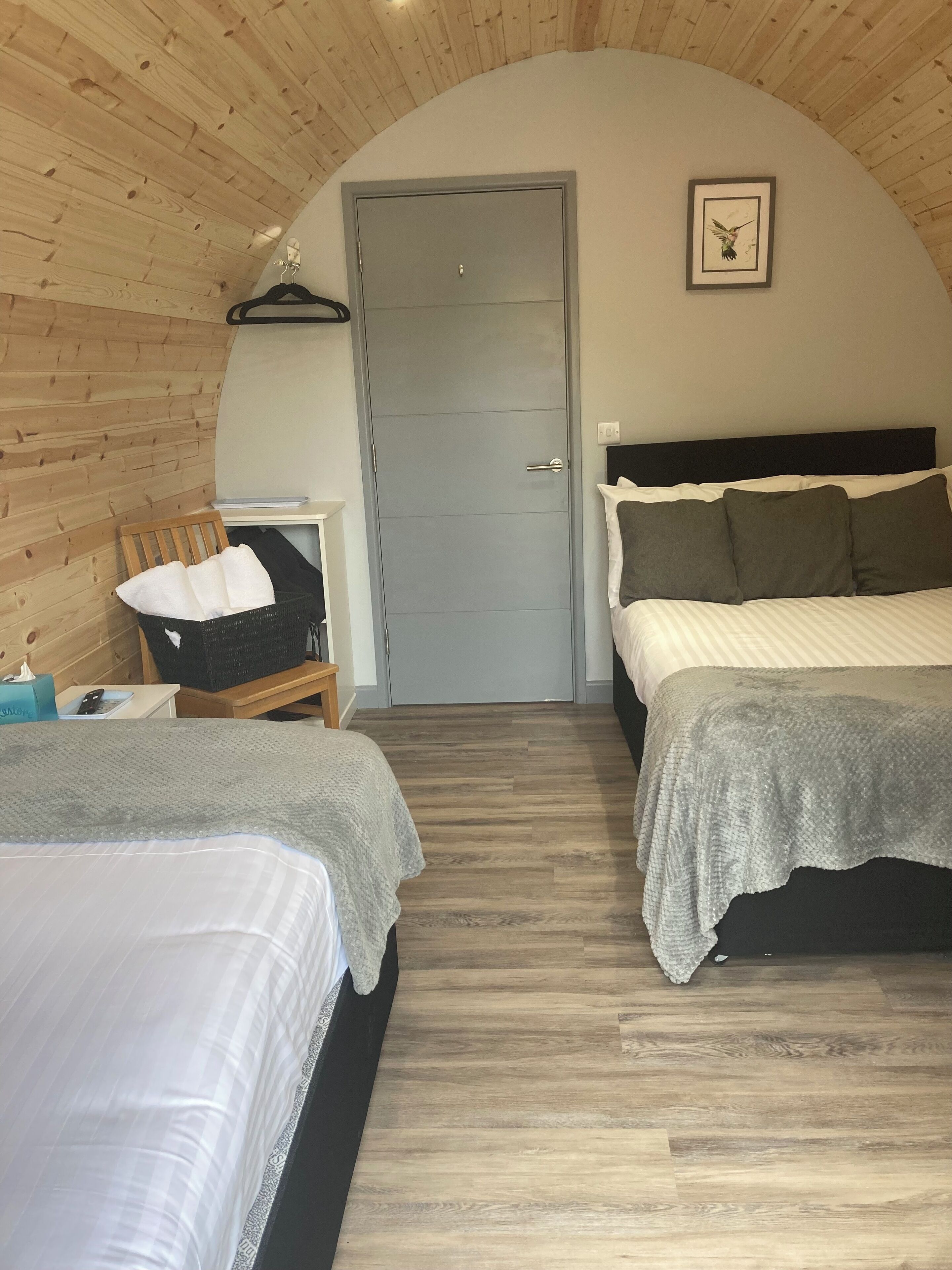 A cozy room with two beds, a wooden ceiling, and a door.