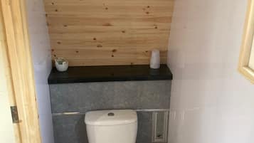 Un baño pequeño con techo de madera, inodoro y lavamanos.