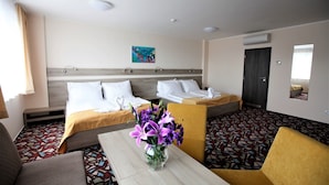 A hotel room with a bed, a sofa, a table with a vase of flowers, and a patterned floor. - Hotel Arena (Chomutov)