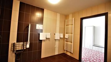 A bathroom with dark brown tiles, a towel rack, a towel warmer, and a glass shower enclosure.