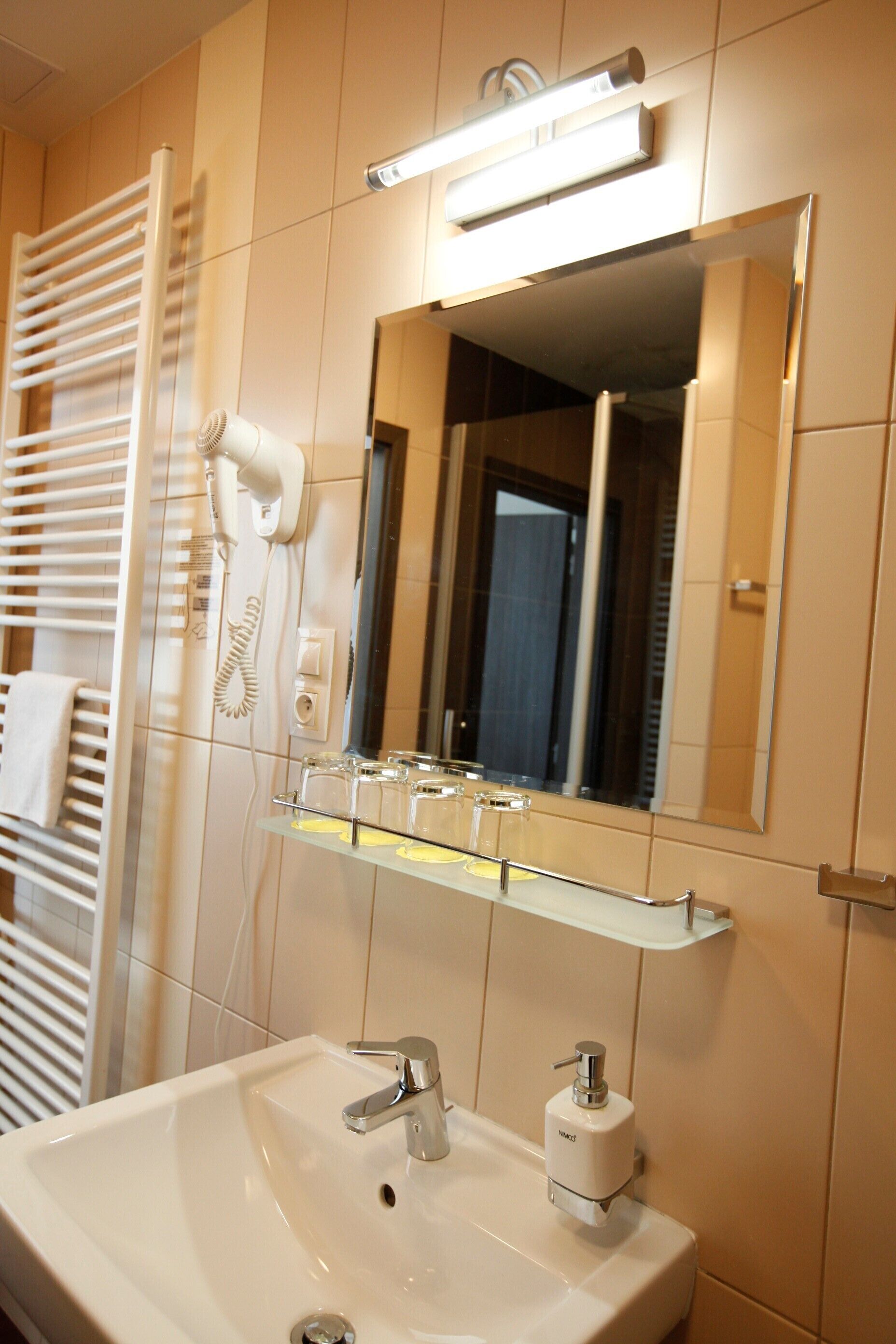 A bathroom with a white sink, a mirror, a hairdryer, and a towel rack.