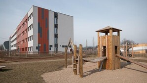 A playground with a wooden climbing structure and a slide, adjacent to a multi-story building with a modern design. - Hotel Arena (Chomutov)