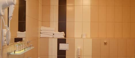 Un baño moderno con lavamanos, inodoro, bidé y un secador de pelo sobre un soporte.