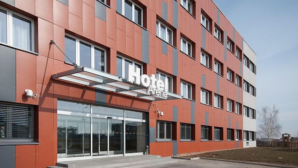 A modern hotel building with a red facade, large glass entrance, and multiple windows. - Hotel Arena (Chomutov)