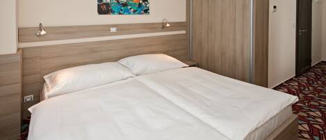 Ein Hotelzimmer mit einem großen Bett, einem Kleiderschrank, einem Bild an der Wand und einem gemusterten Teppich.