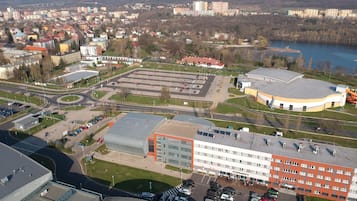 An aerial view of a cityscape with a prominent red building, a roundabout, and a body of water in the background.