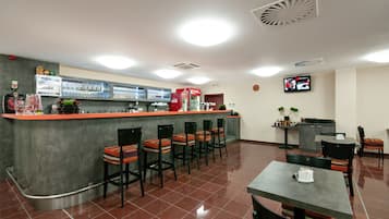 A restaurant with a bar area, multiple seating arrangements, and a television screen on the wall.