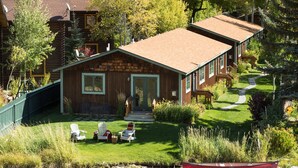 A lodge with a wooden exterior, a grassy front yard, and a boat on the water. - Outpost: Alpine Cottage Four (Jackson)