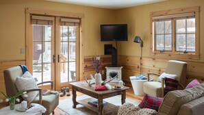A cozy living room with a fireplace, comfortable seating, and a television. - Outpost: Alpine Cottage Four (Jackson)