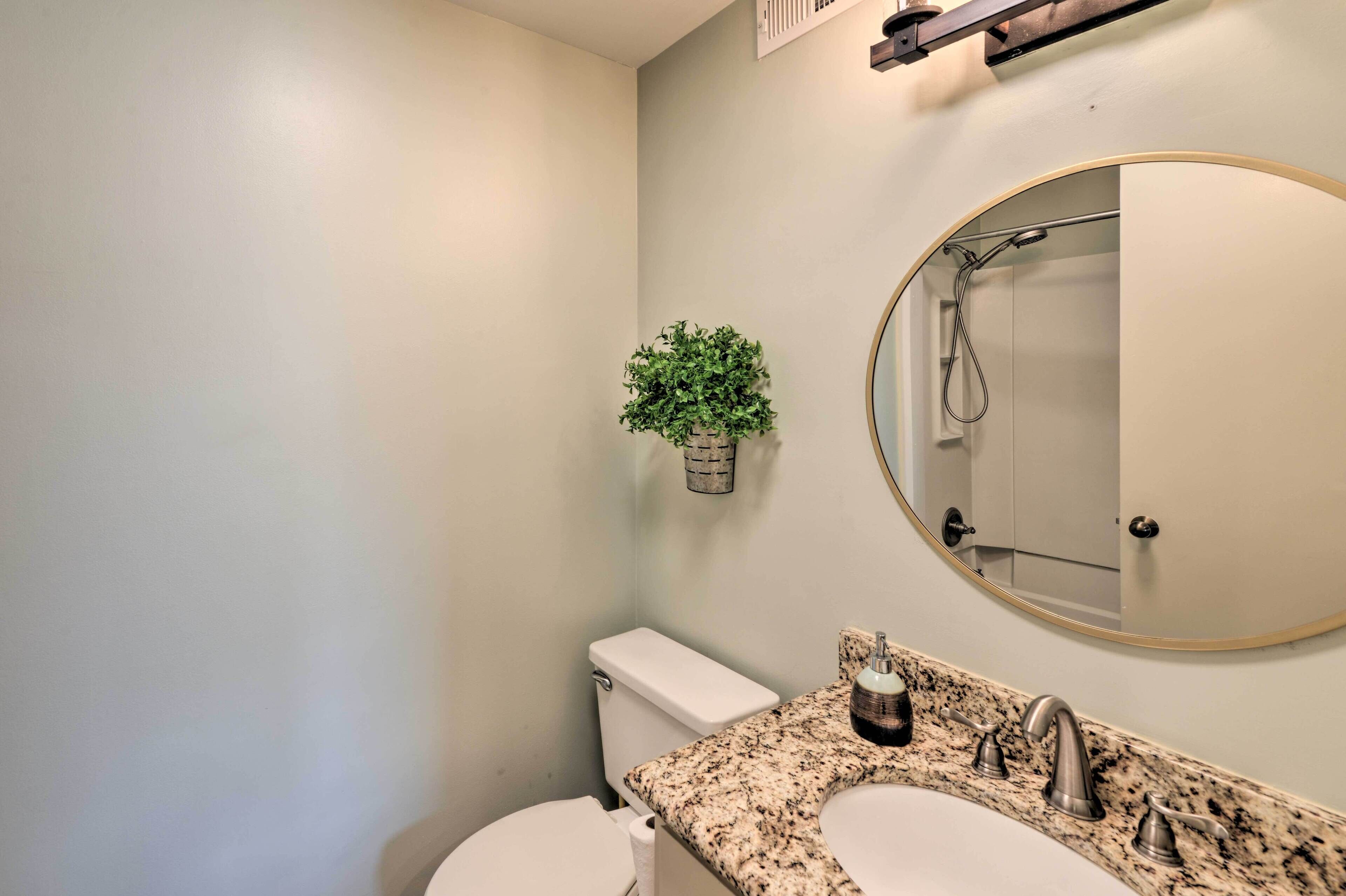 A bathroom with a toilet, sink, and a mirror.