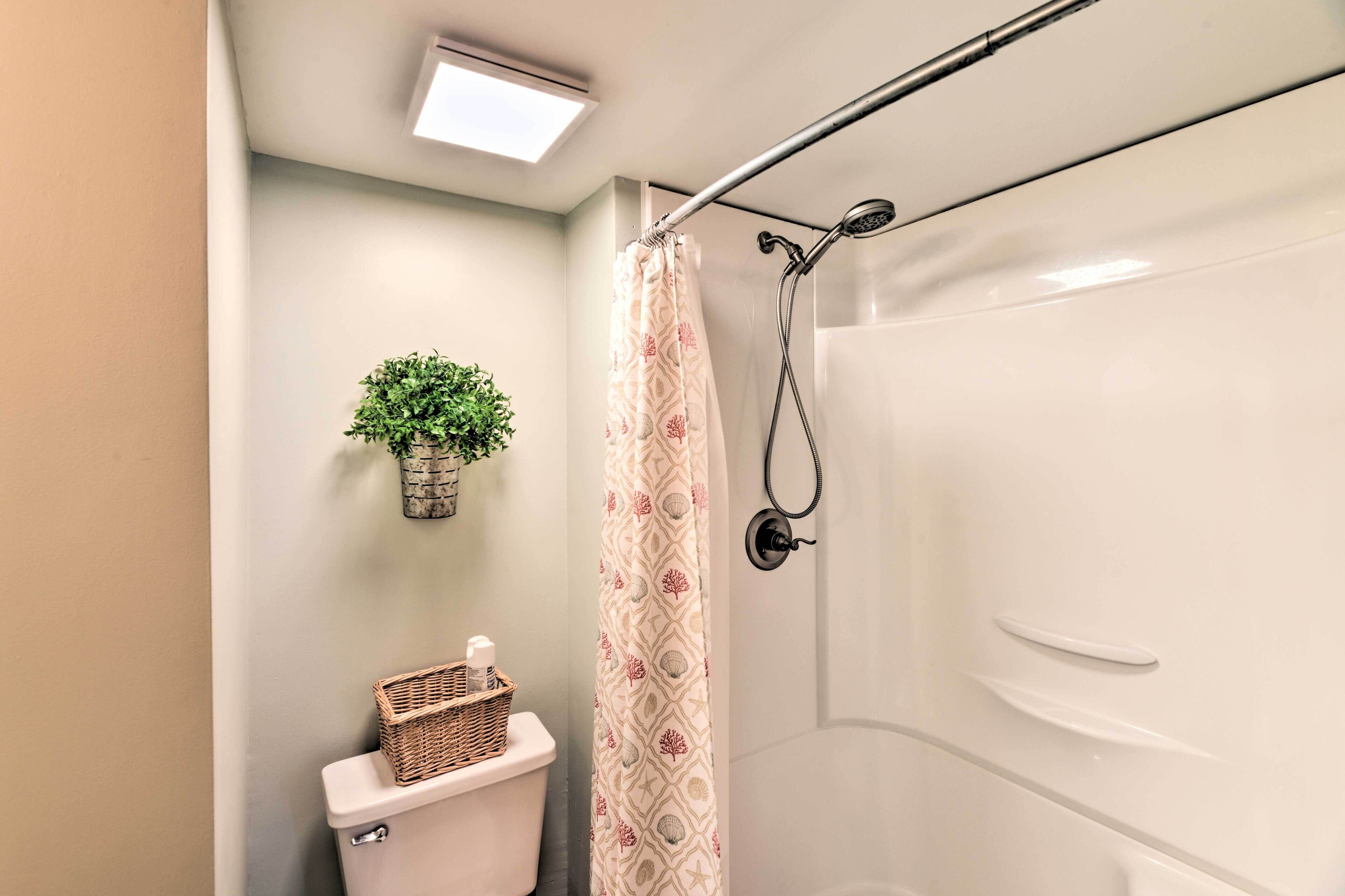Ein Badezimmer mit Dusche, Toilette und einer kleinen Pflanze an der Wand.