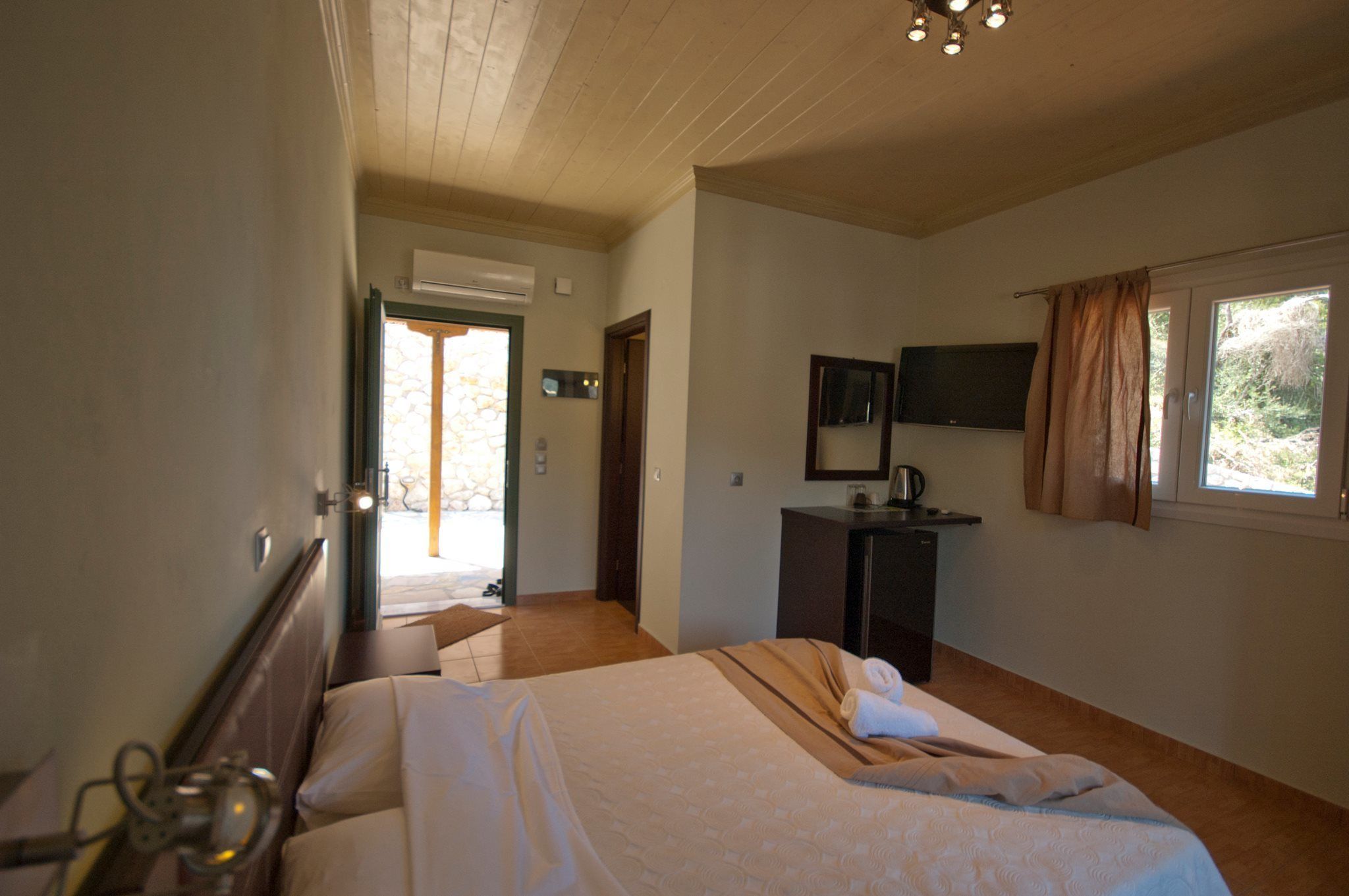 A hotel room with a bed, a desk, a mirror, and a window with curtains.