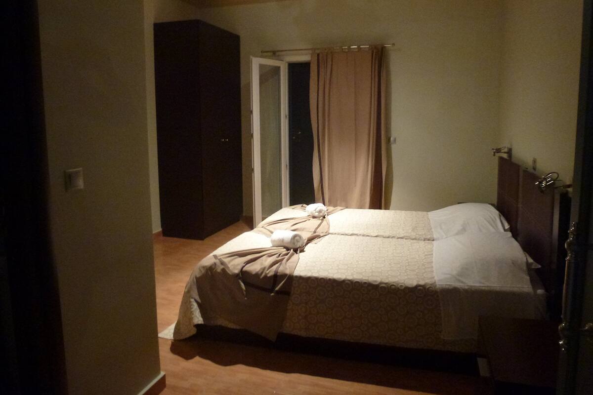 A bedroom with a bed, a wardrobe, and a door leading to another room.