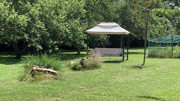 A gazebo with a canopy, surrounded by lush greenery and trees.