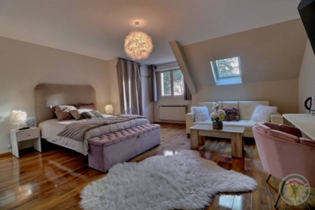 A bedroom with a bed, a nightstand, a dresser, a fluffy rug, a coffee table, and a window with curtains.